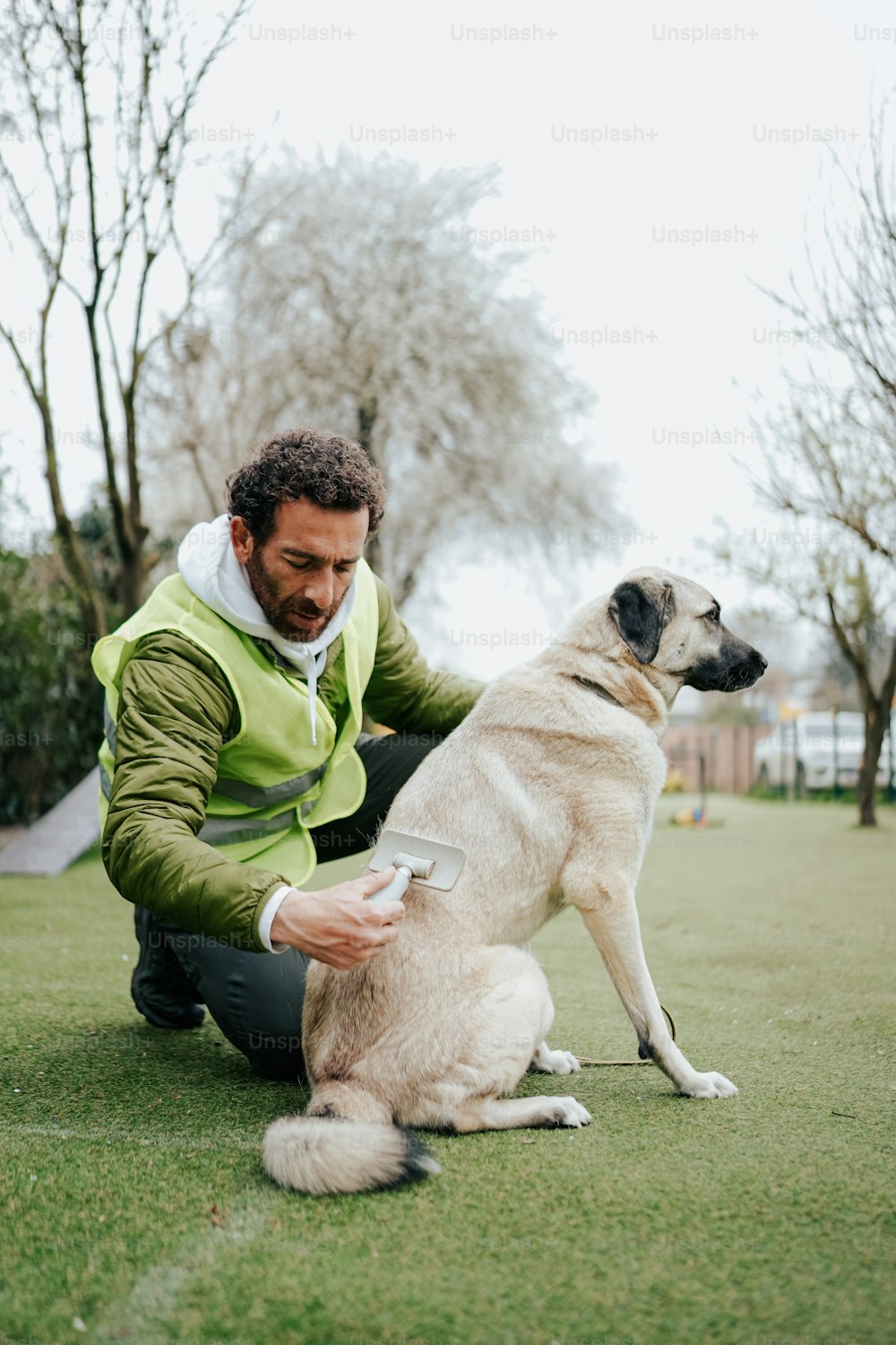 a man kneeling down next to a dog on a field