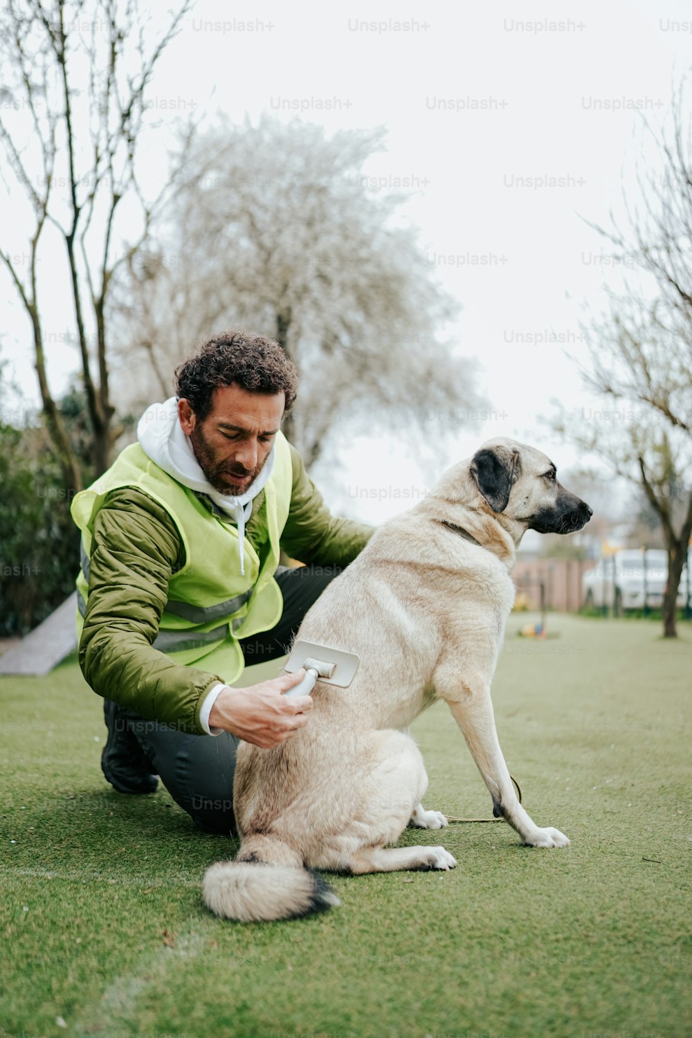 um homem ajoelhado ao lado de um cão em um campo