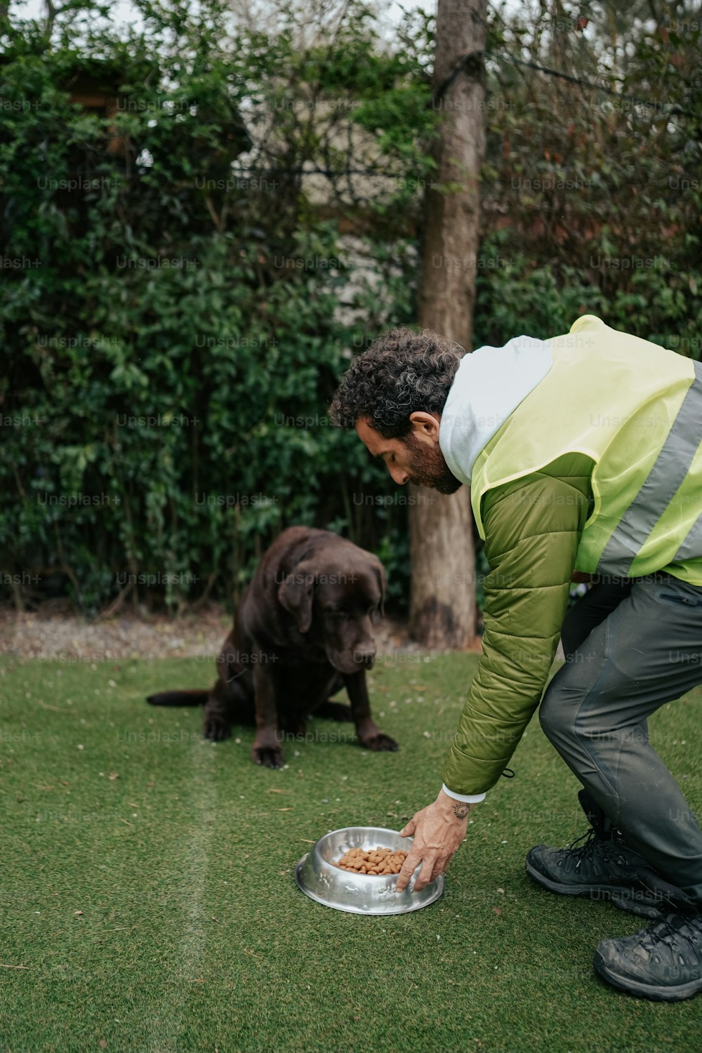 a man feeding a dog food out of a bowl