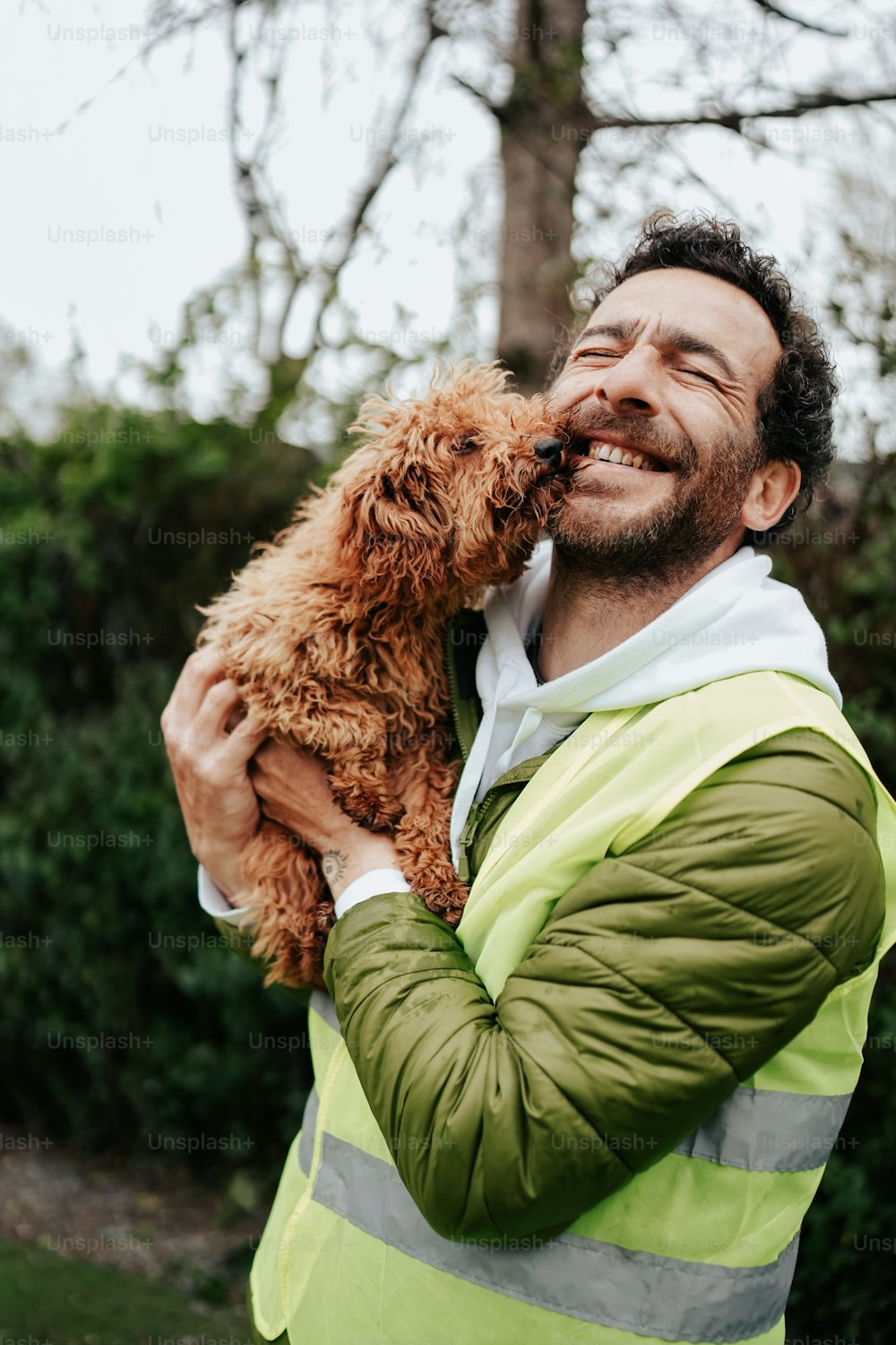 a man in a yellow vest holding a brown dog