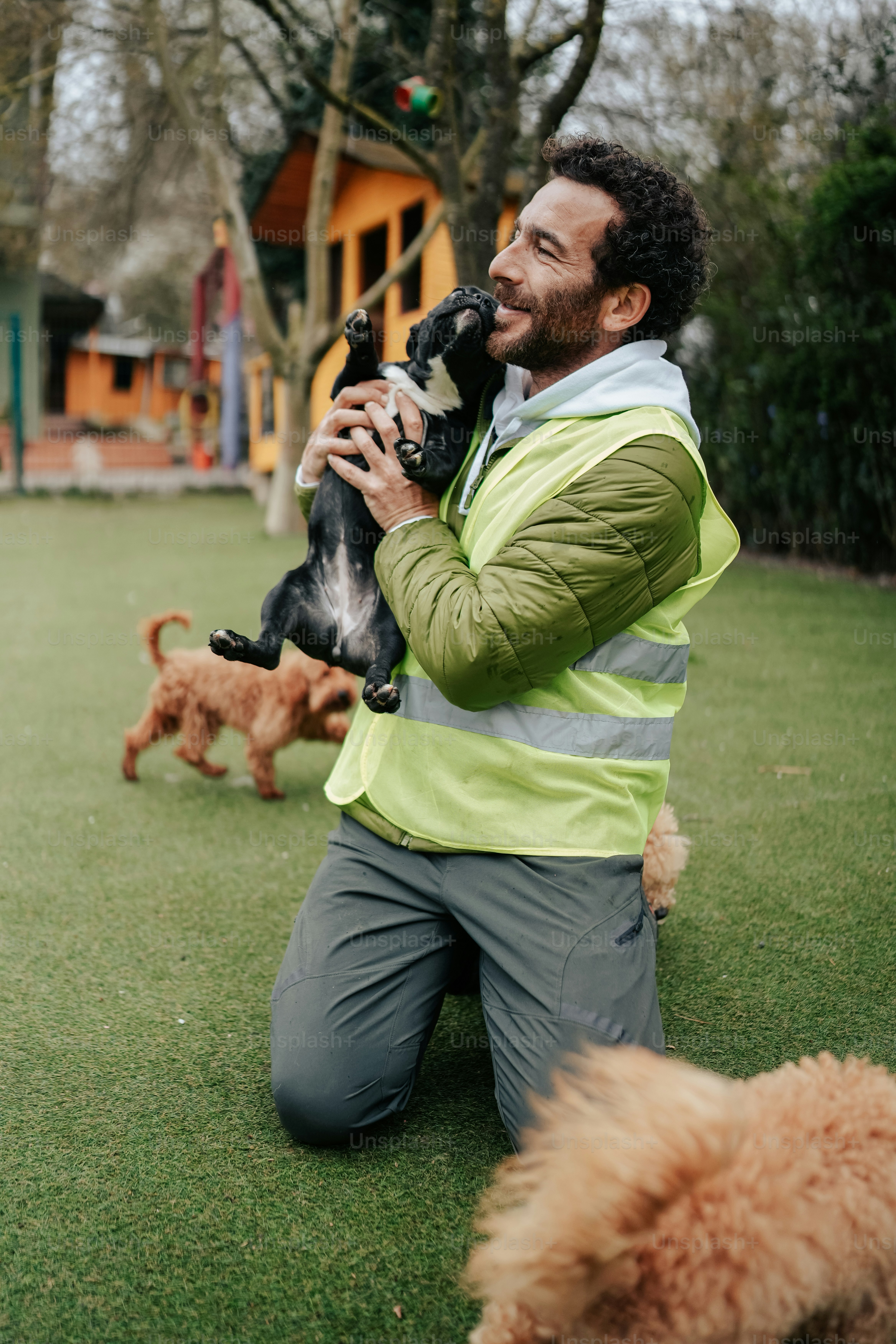 a man kneeling down holding a dog in his hands