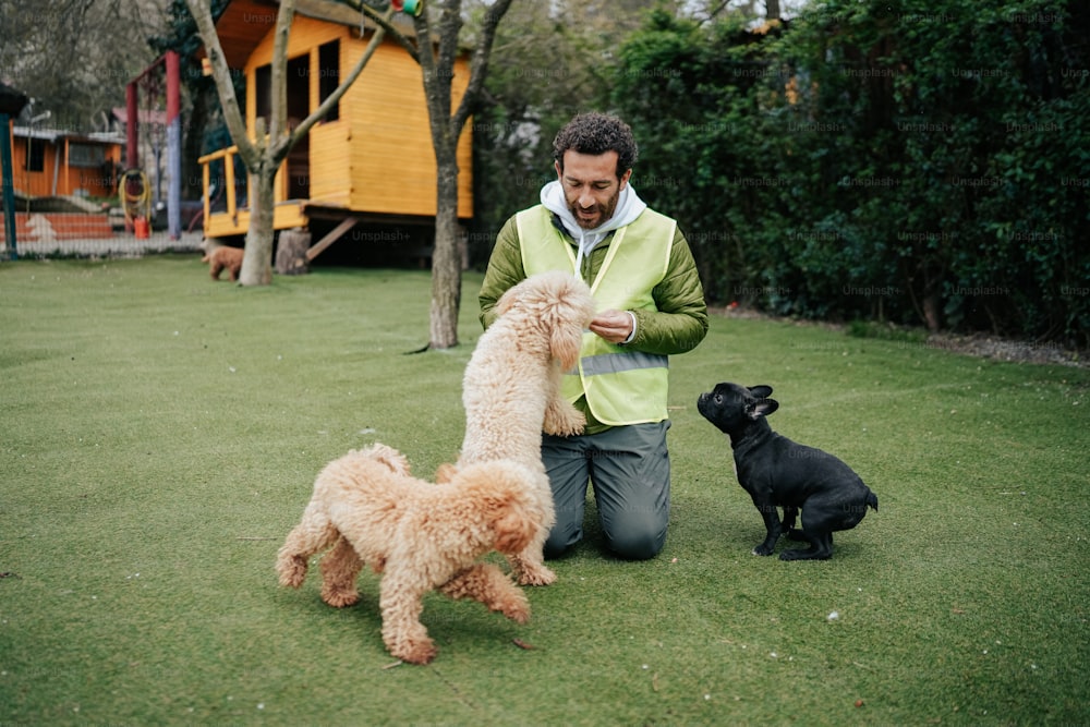 a man kneeling down next to three dogs