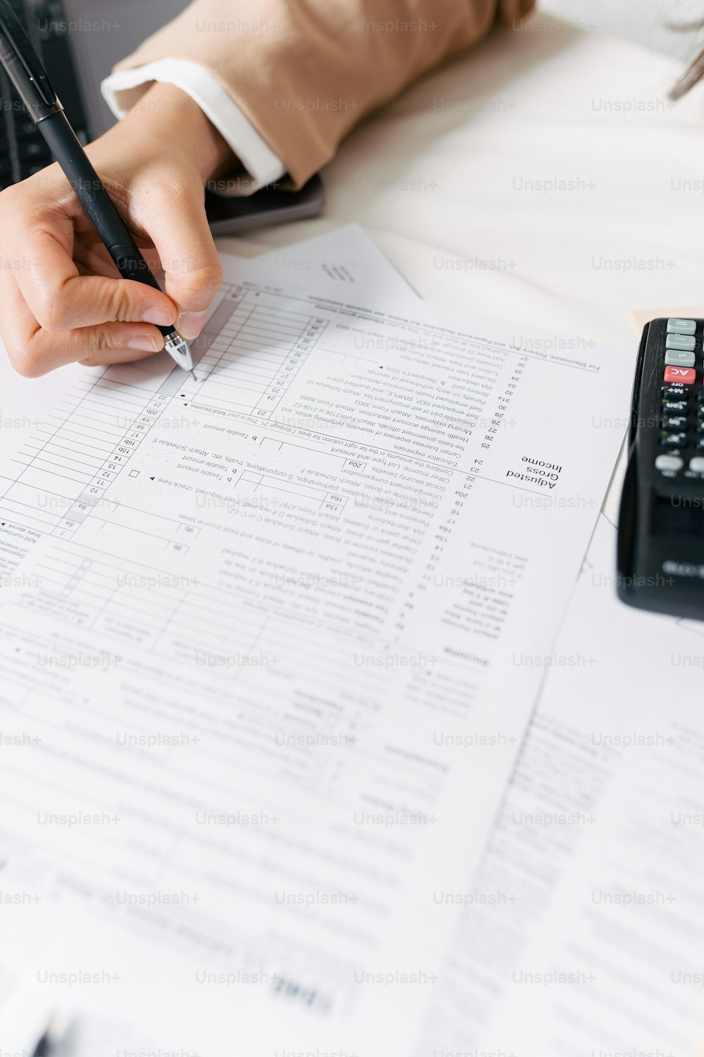 a person sitting at a desk with a calculator and pen