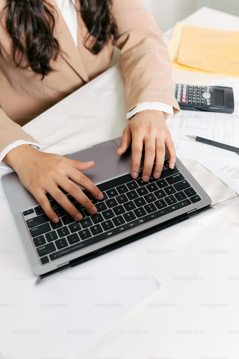 a woman sitting at a desk typing on a laptop