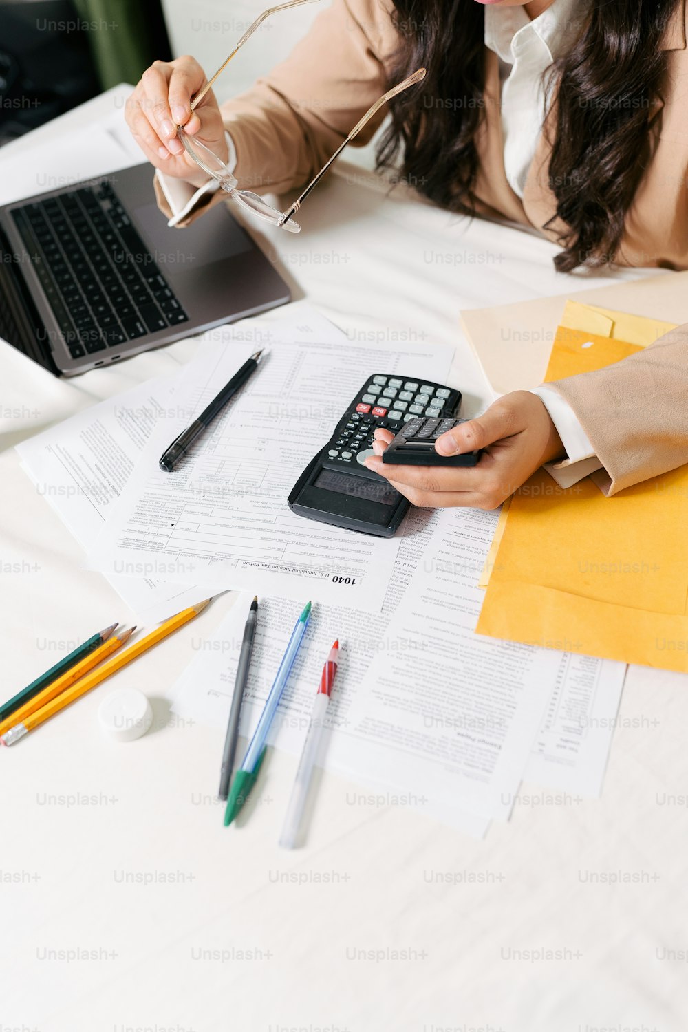 a woman sitting at a desk with a calculator and a laptop