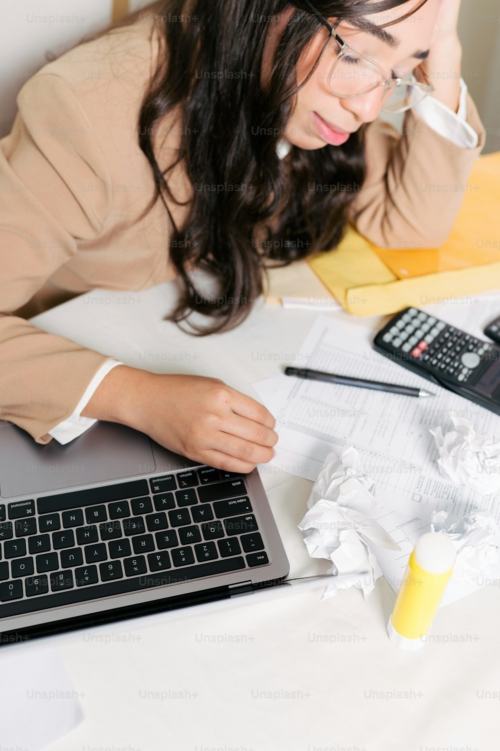 Una mujer sentada en un escritorio con una computadora portátil y una calculadora