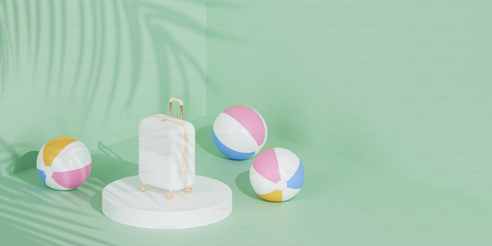 three beach balls and a suitcase on a green background
