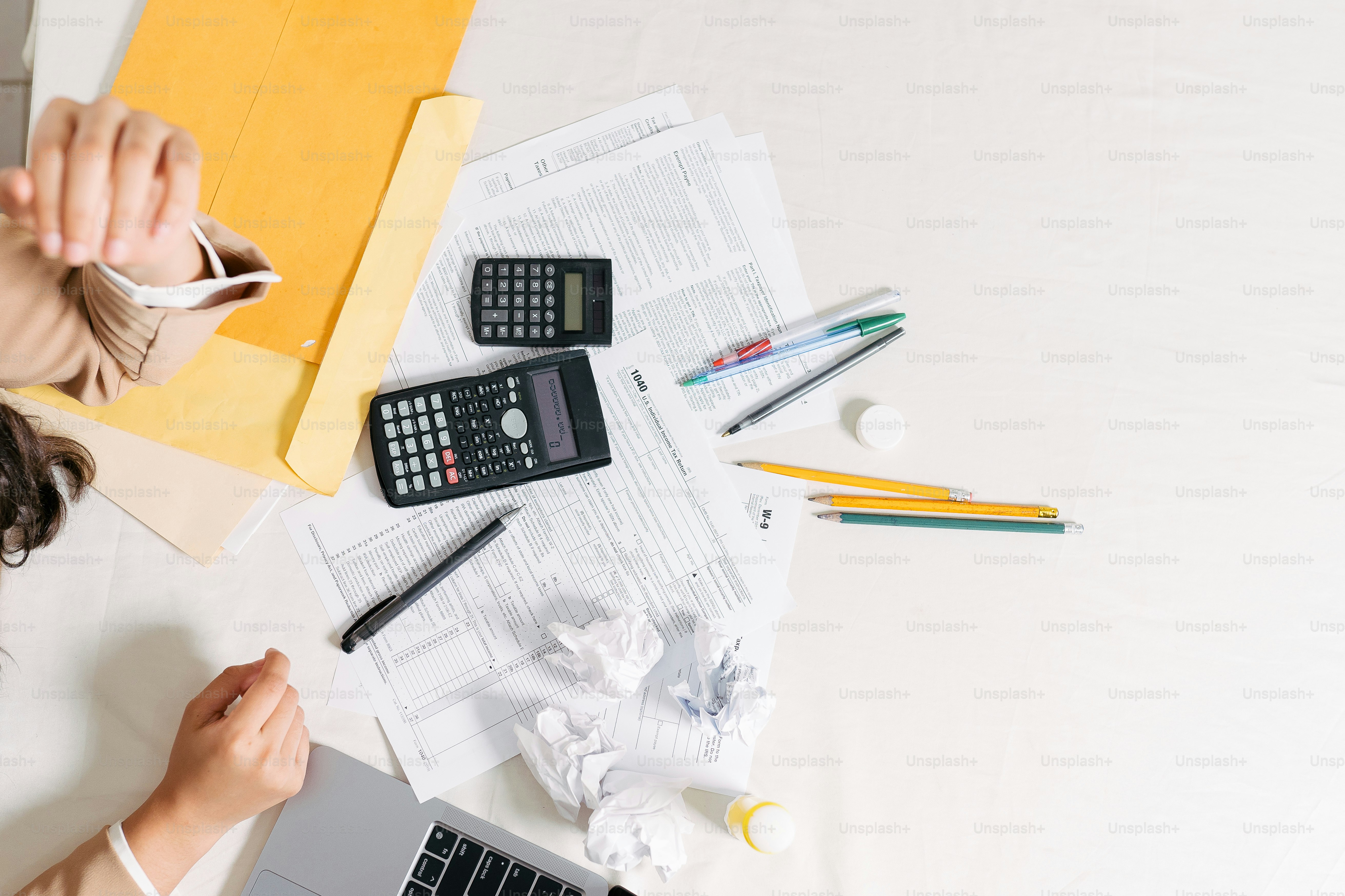 a woman sitting at a desk with a calculator and a laptop