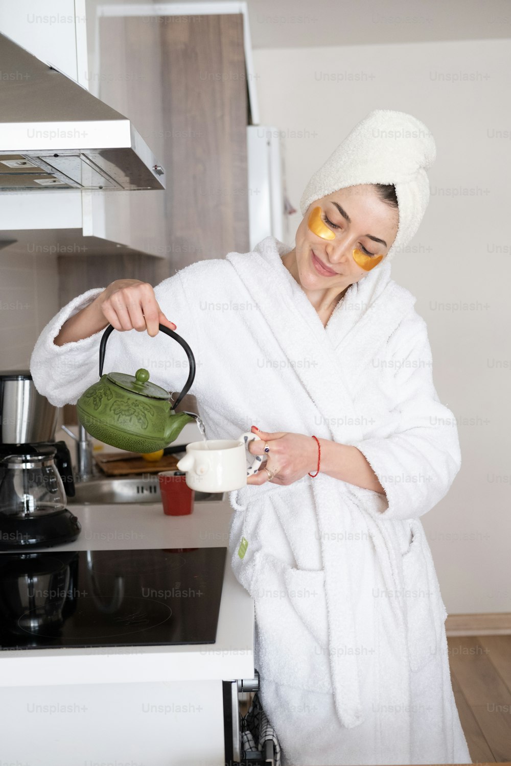 a woman in a bathrobe pouring tea into a cup