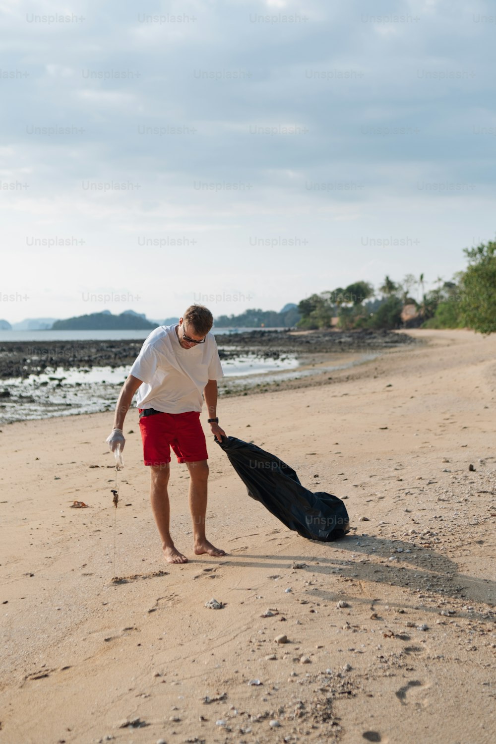 a man walking on a beach with a bag of luggage