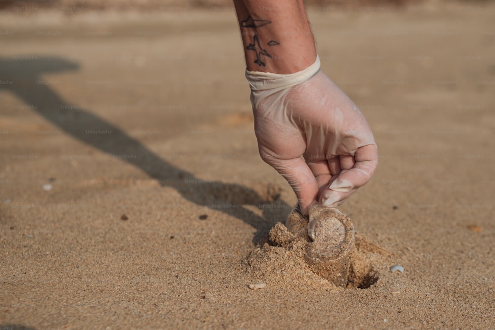 a person with a tattoo on their arm reaching for a ball in the sand