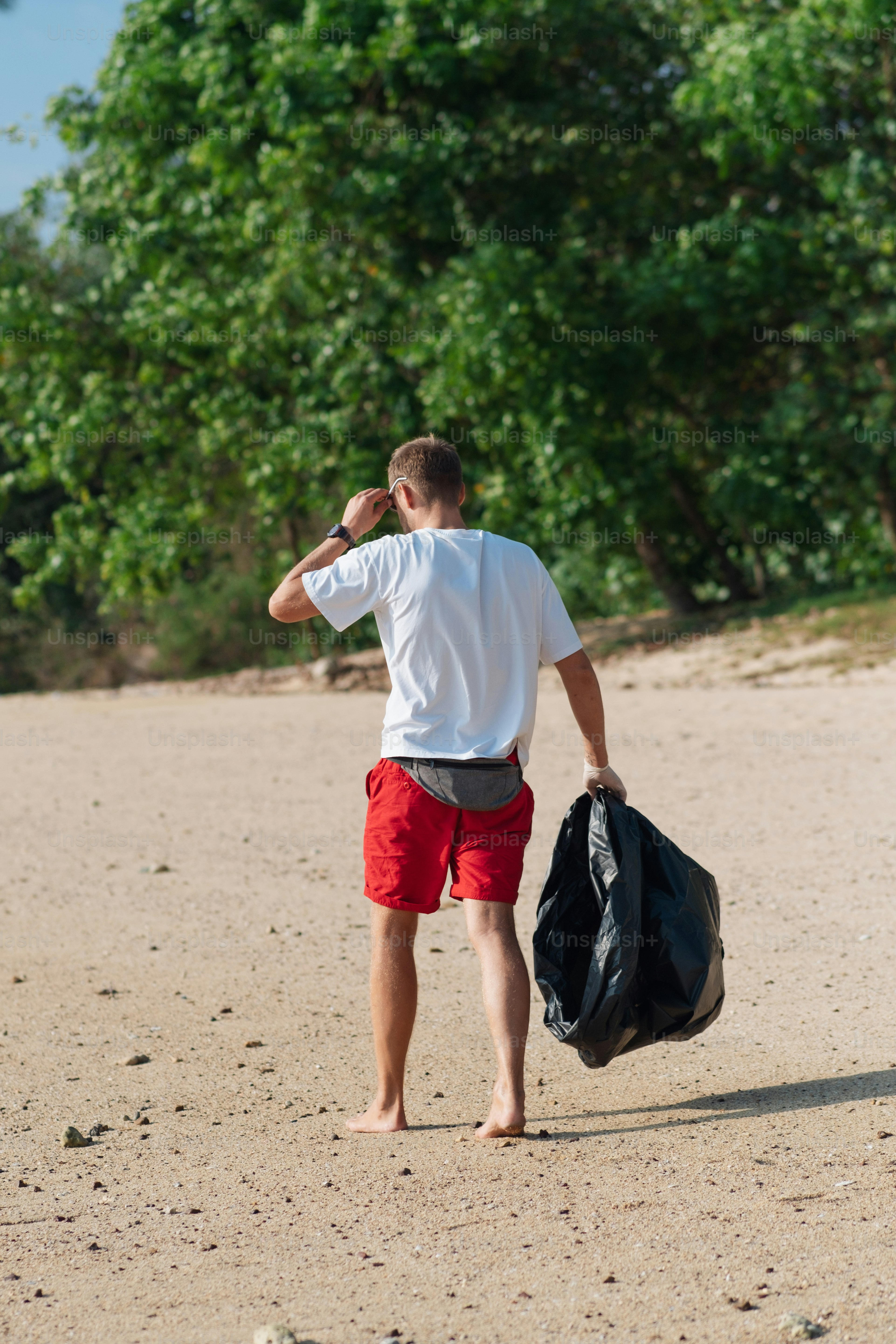 a man in red shorts and a white shirt carrying a black bag
