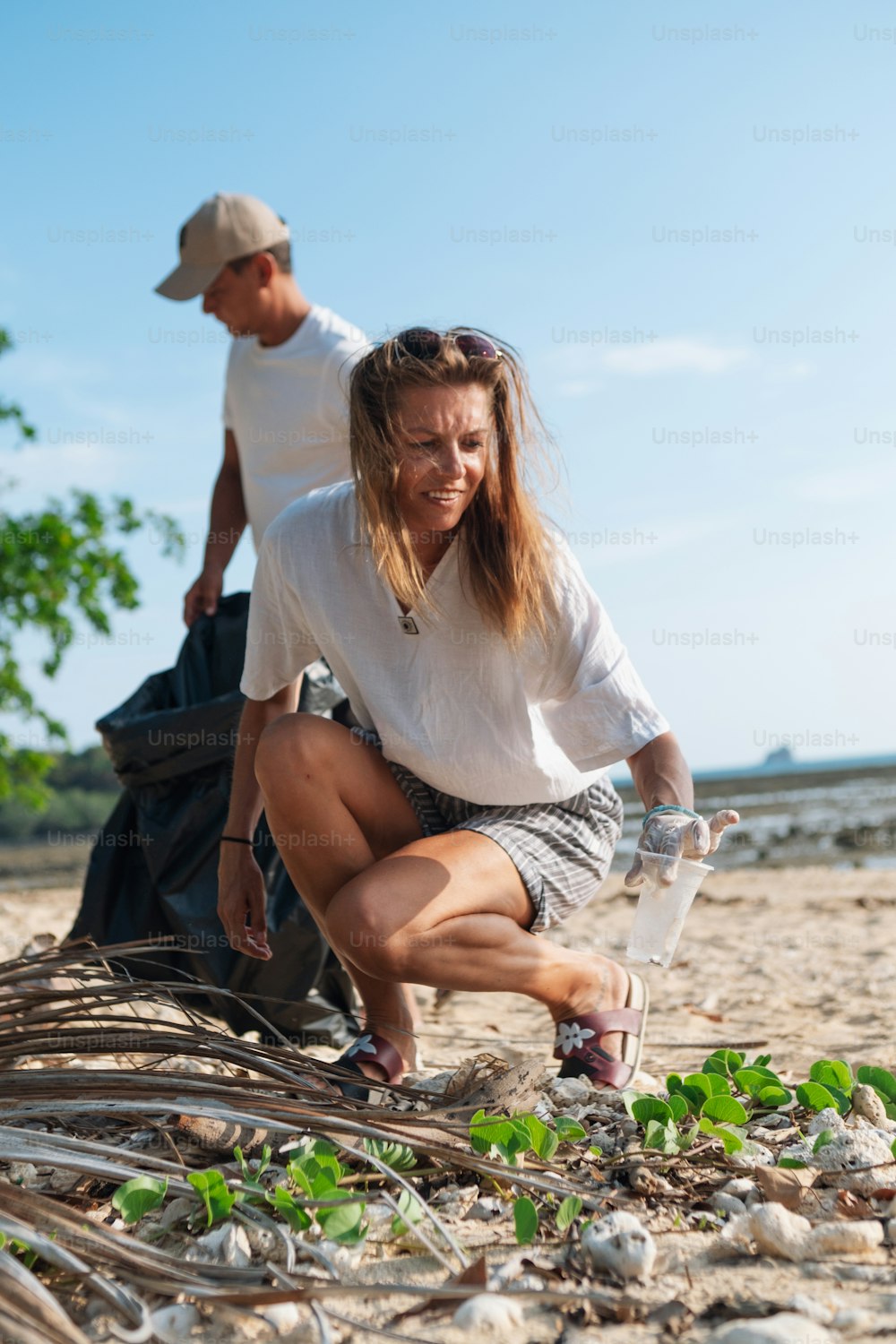 Un homme et une femme sur la plage ramassant des algues