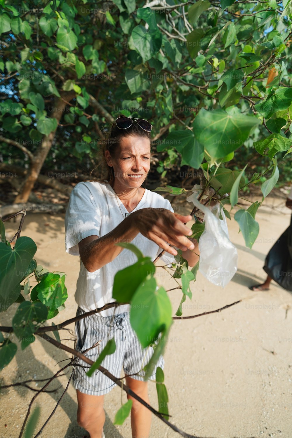 Eine Frau, die eine Plastiktüte unter einem Baum hält
