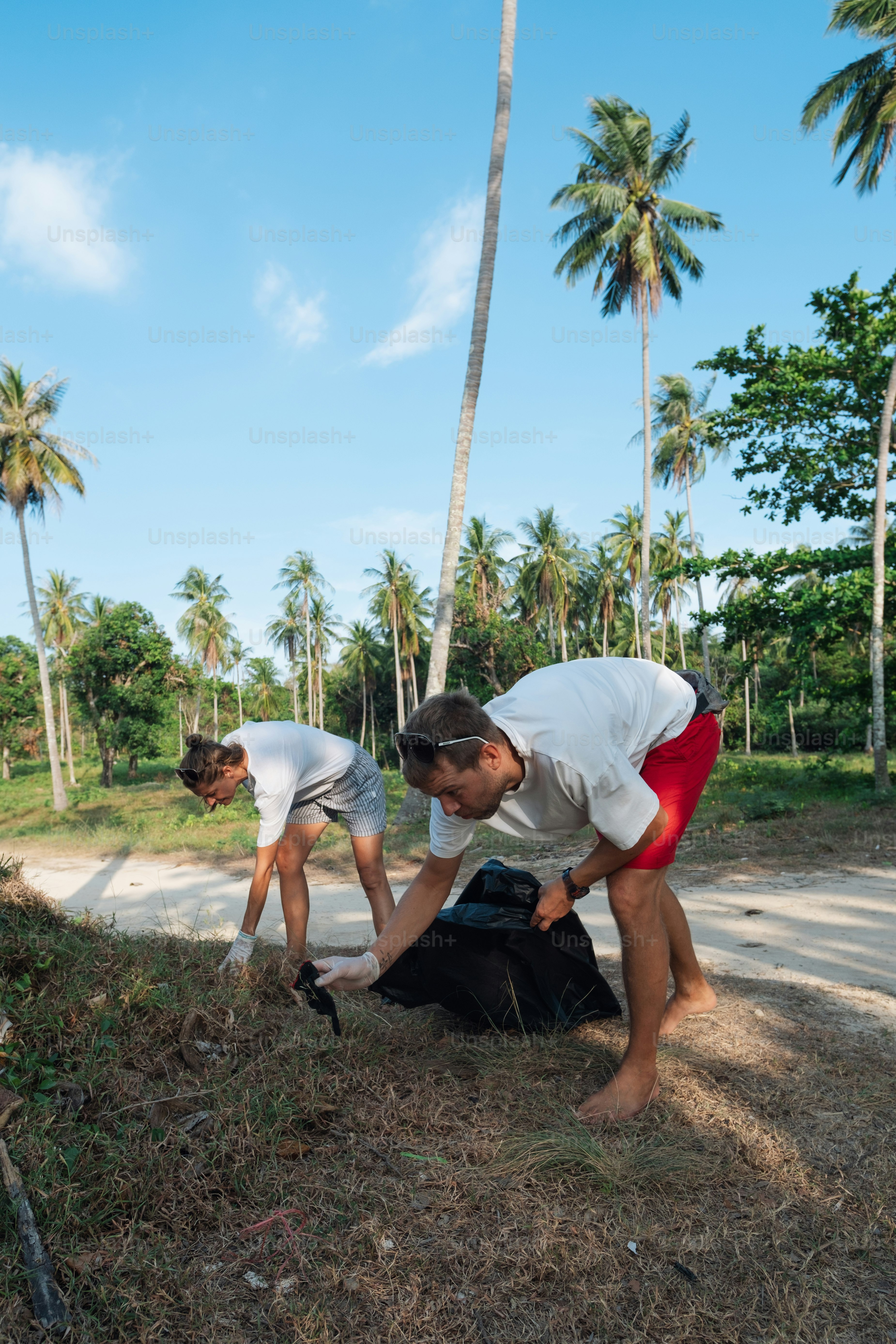 Dua pria sedang memungut sampah di pinggir jalan