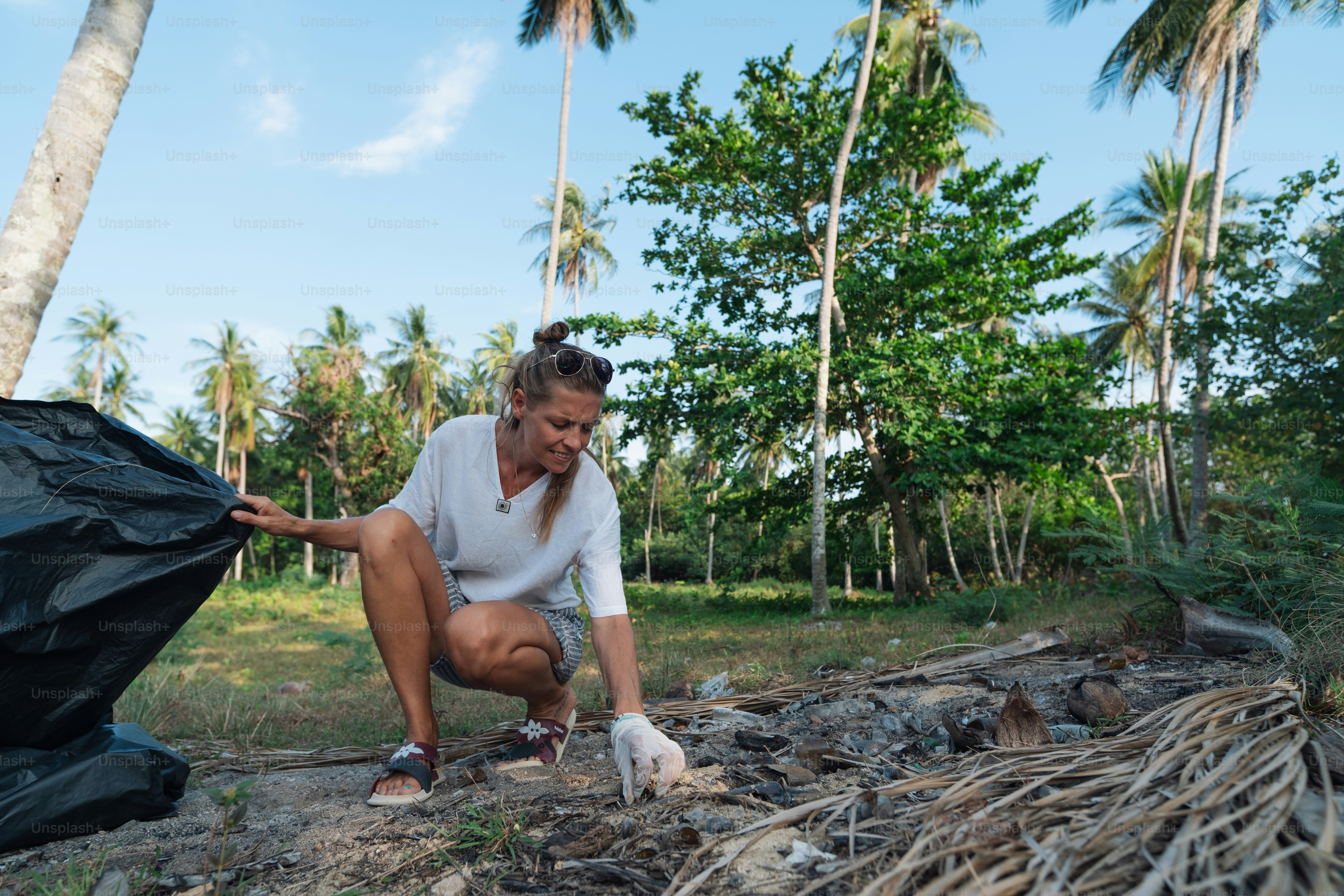 a woman kneeling down next to a pile of trash