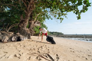 a man standing on a beach next to a tree