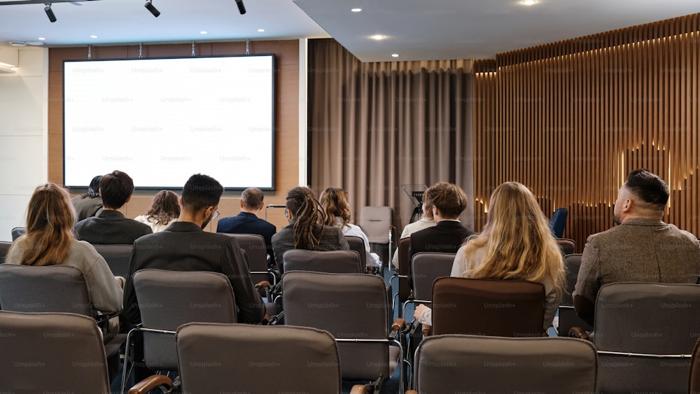 a group of people sitting in chairs in front of a projector screen