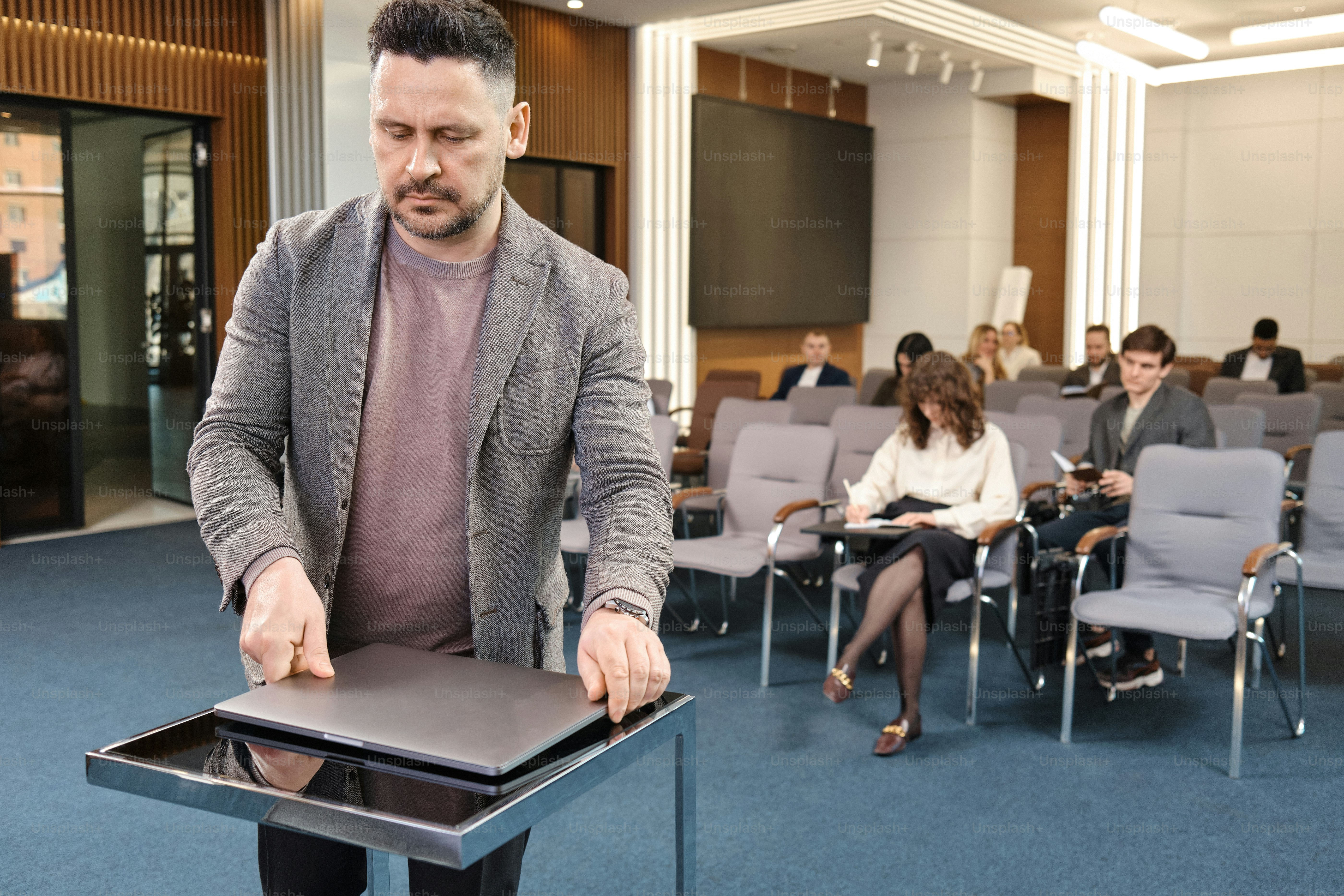 Un hombre parado frente a un podio en una sala llena de gente