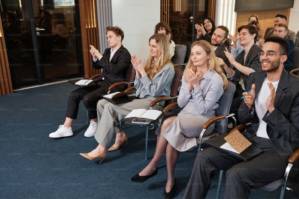 a group of people sitting in chairs clapping