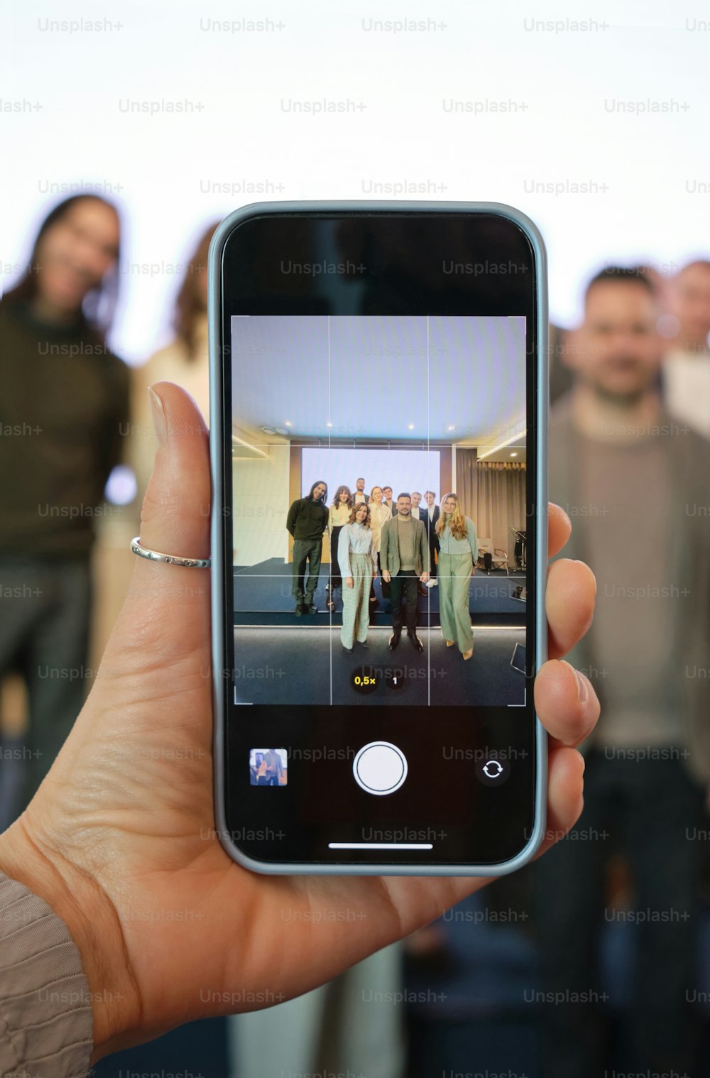 a person holding up a smart phone in front of a group of people