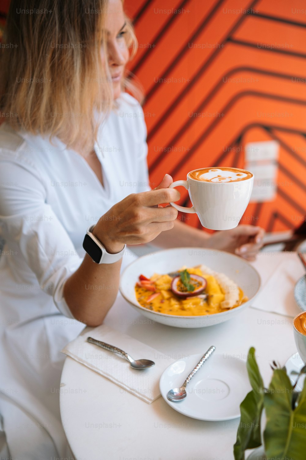 Una mujer sentada en una mesa con un plato de comida y una taza de café
