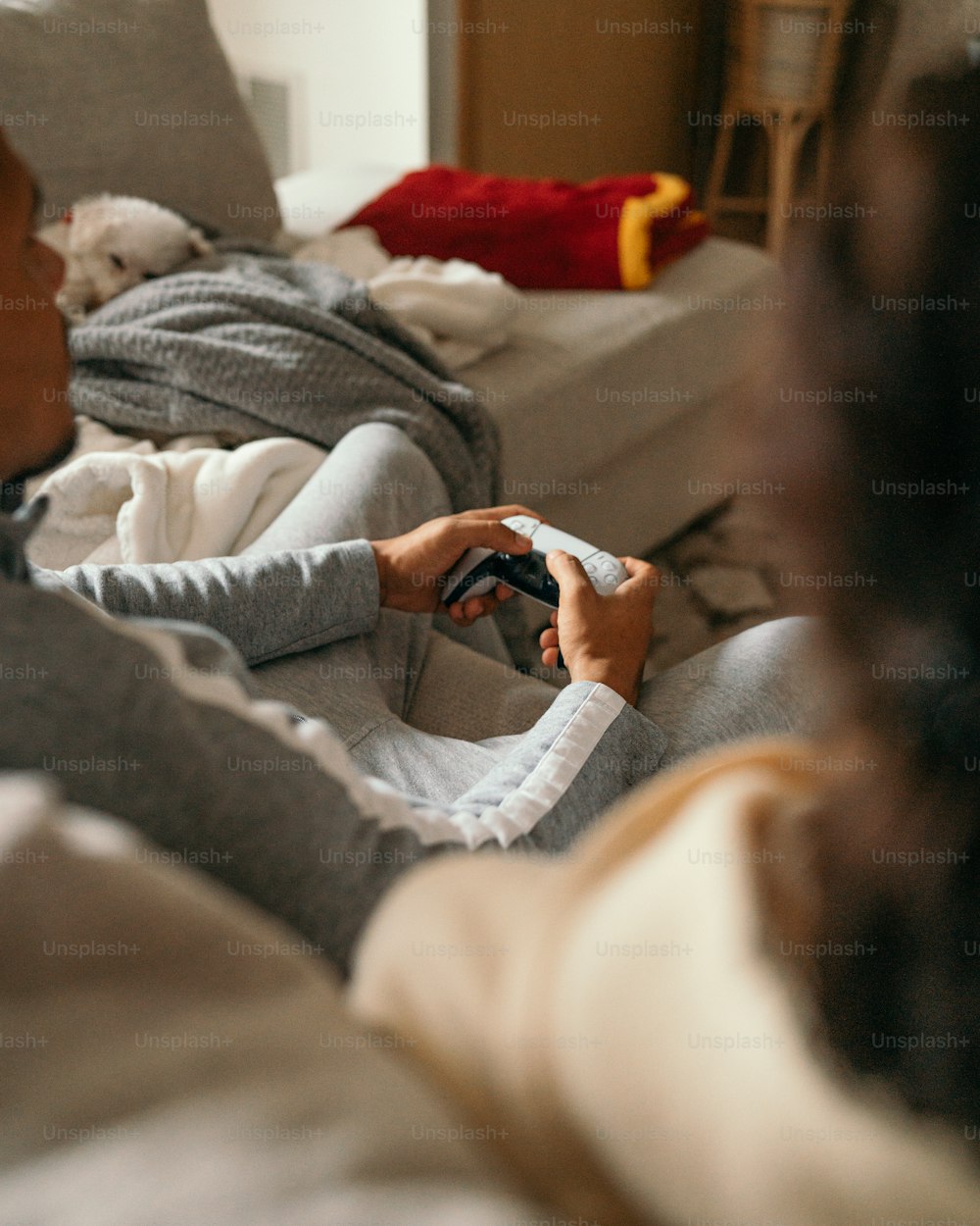 a woman sitting on a couch holding a nintendo wii game controller