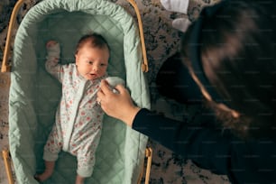 a baby in a crib being brushed by a woman