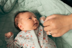 a baby laying in a crib being held by a person