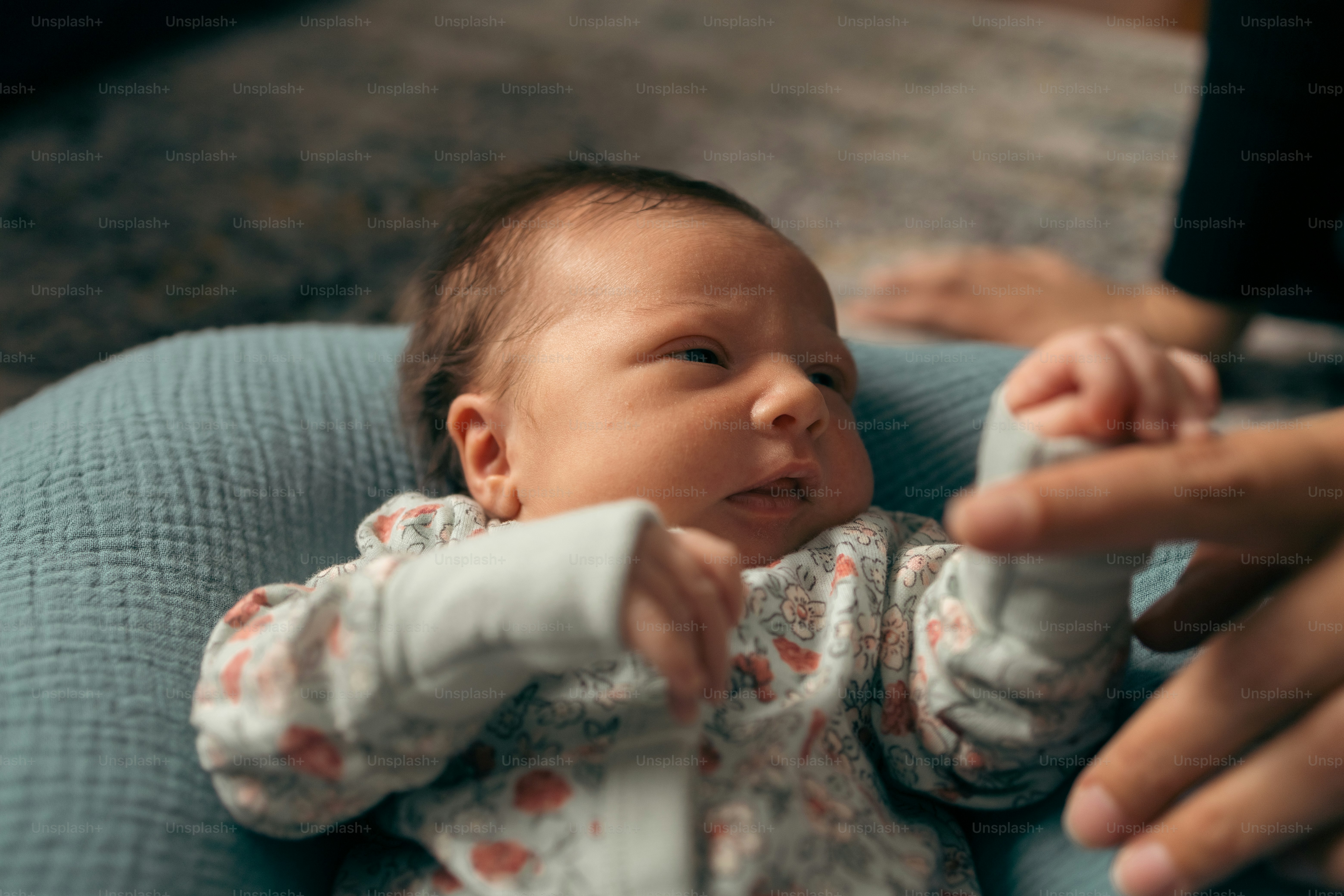 青い椅子に座って人に抱かれている赤ちゃん