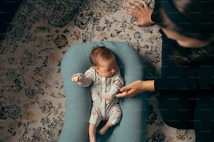여자가 안고 있는 파란색 쿠션에 누워 있는 아기
