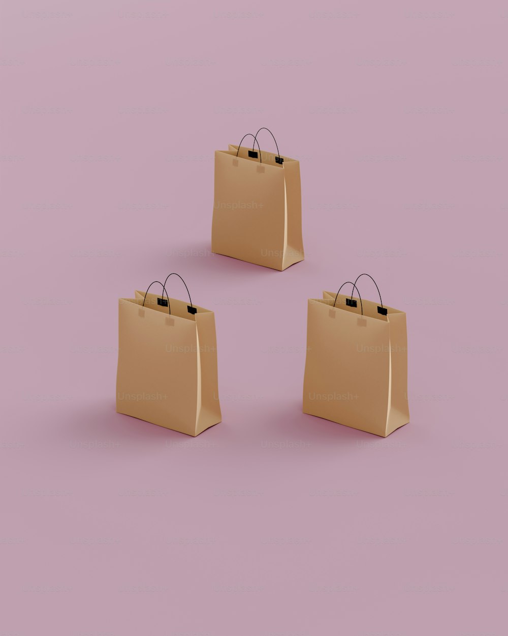 Tres bolsas de compras marrones sobre un fondo rosa