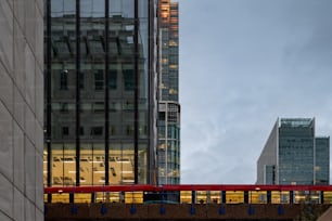 a red train traveling over a bridge next to tall buildings