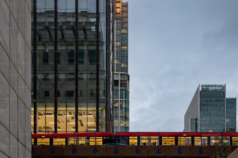 a red train traveling over a bridge next to tall buildings