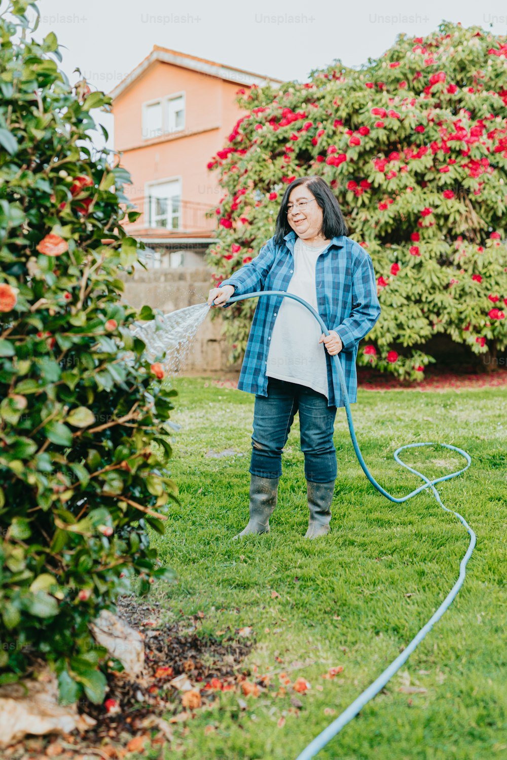 a woman watering her garden with a hose