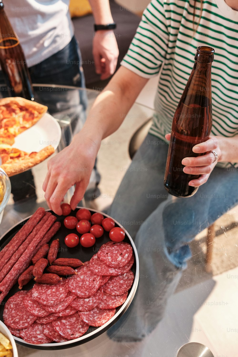 a man holding a bottle of beer over a platter of food