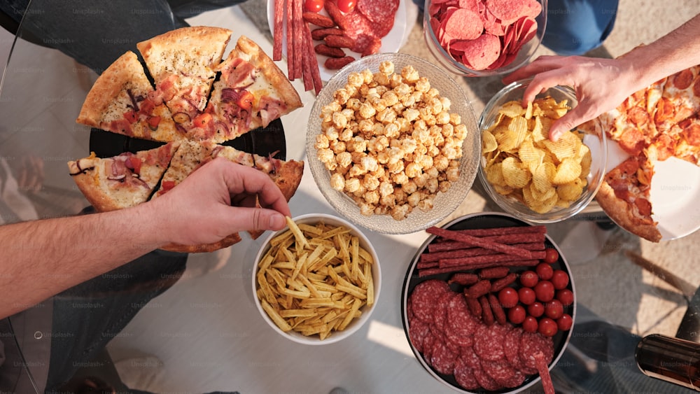 a group of people eating pizza and other foods