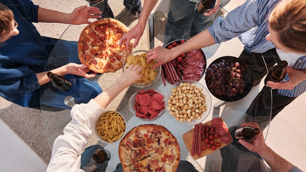 a group of people standing around a table filled with food