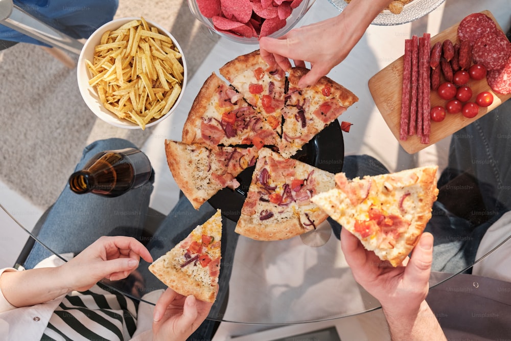 a group of people holding slices of pizza