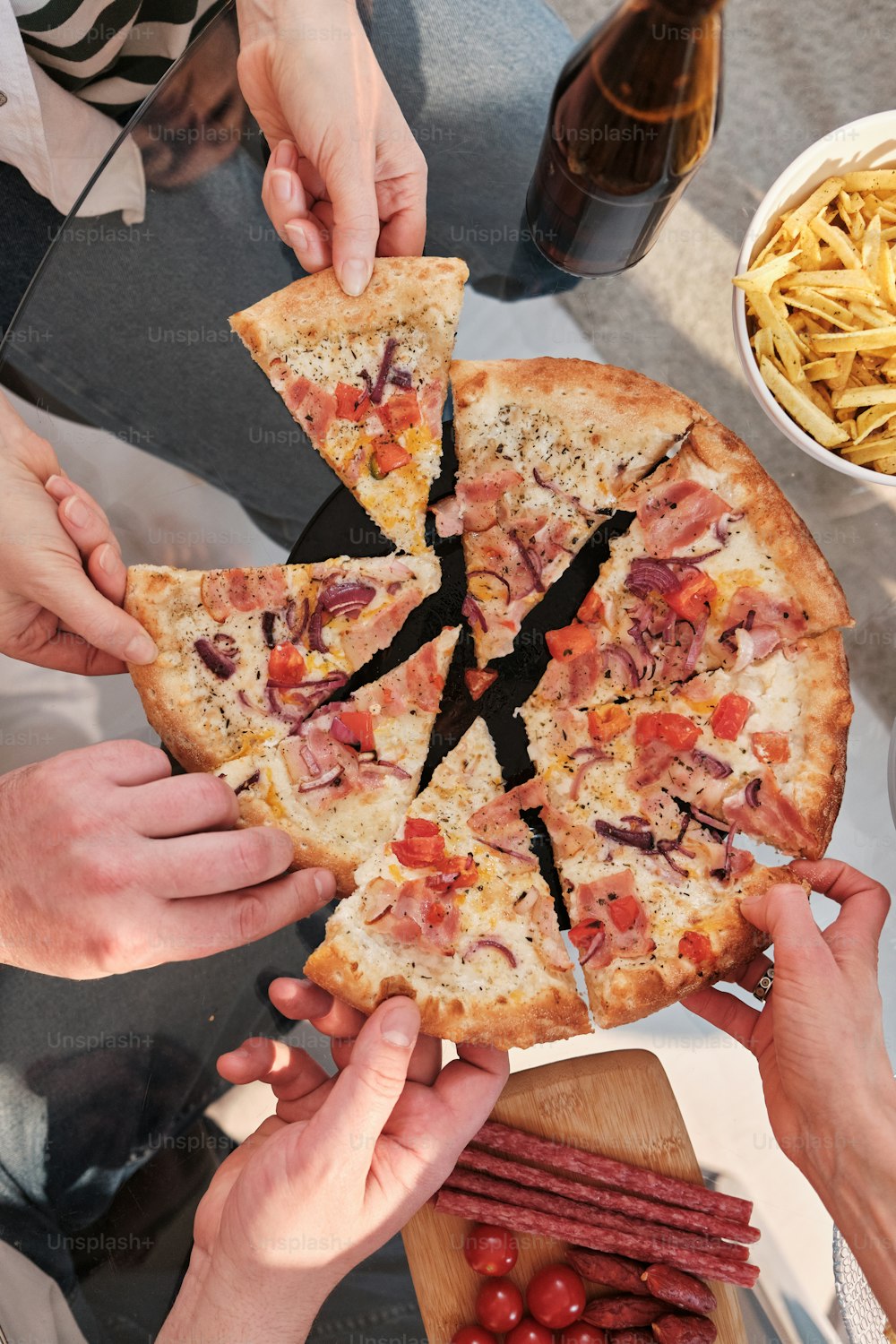 a group of people holding a pizza with a slice taken out of it