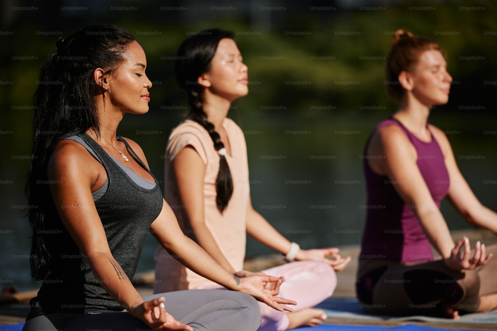 um grupo de mulheres sentadas em cima de tapetes de yoga