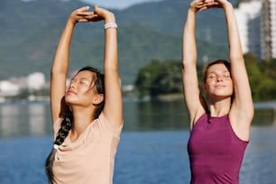 Zwei junge Frauen machen Yoga-Übungen am Wasser