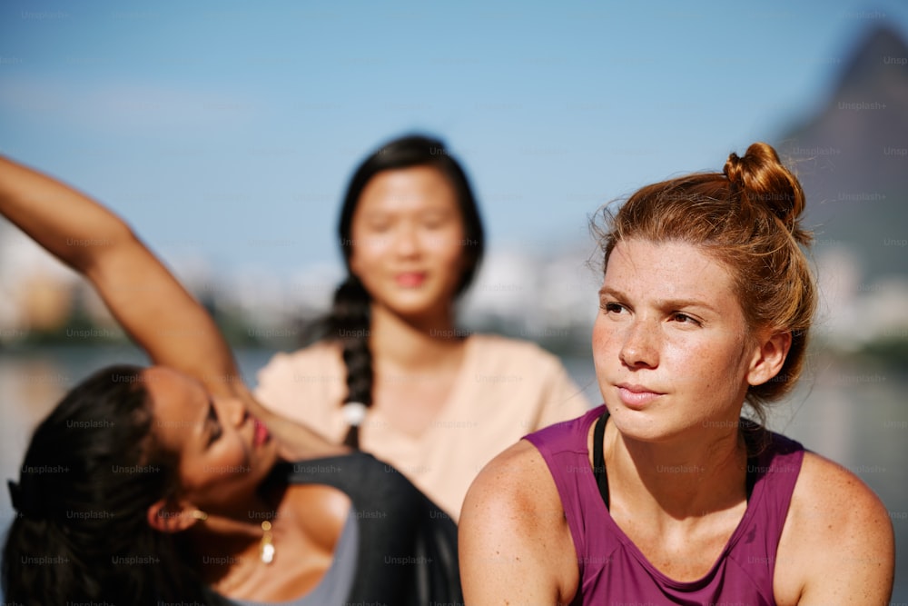 two women sitting next to each other near a body of water