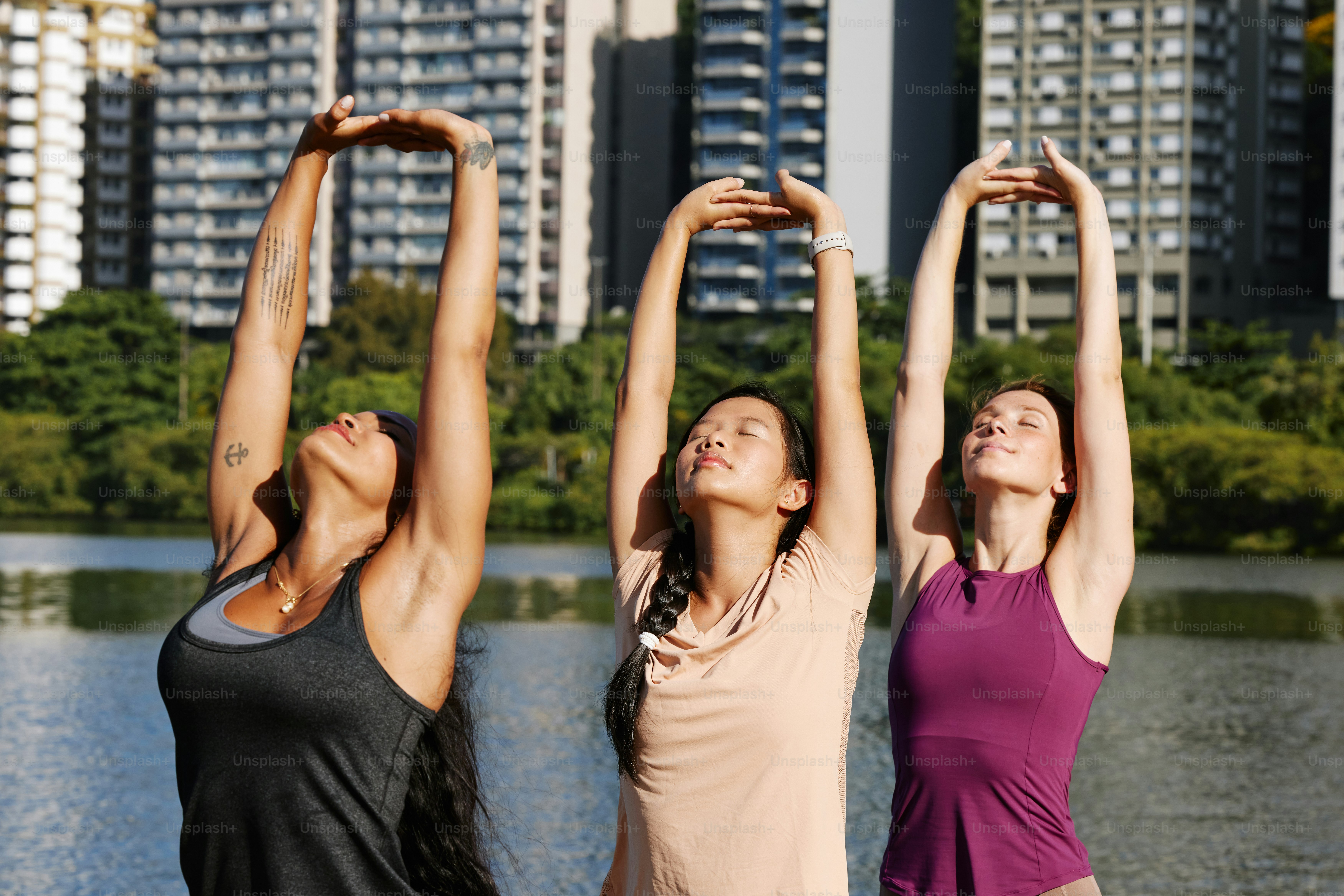 three women doing yoga in front of a body of water