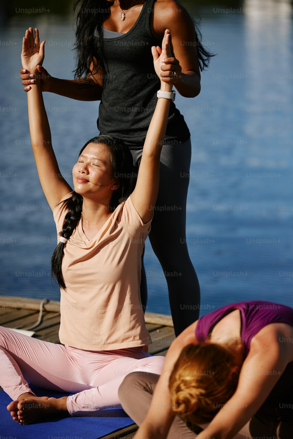 two women doing yoga on a dock near a body of water