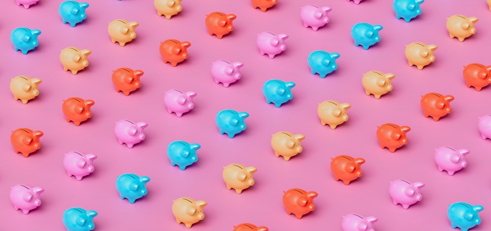 a group of colorful piggy banks on a pink background