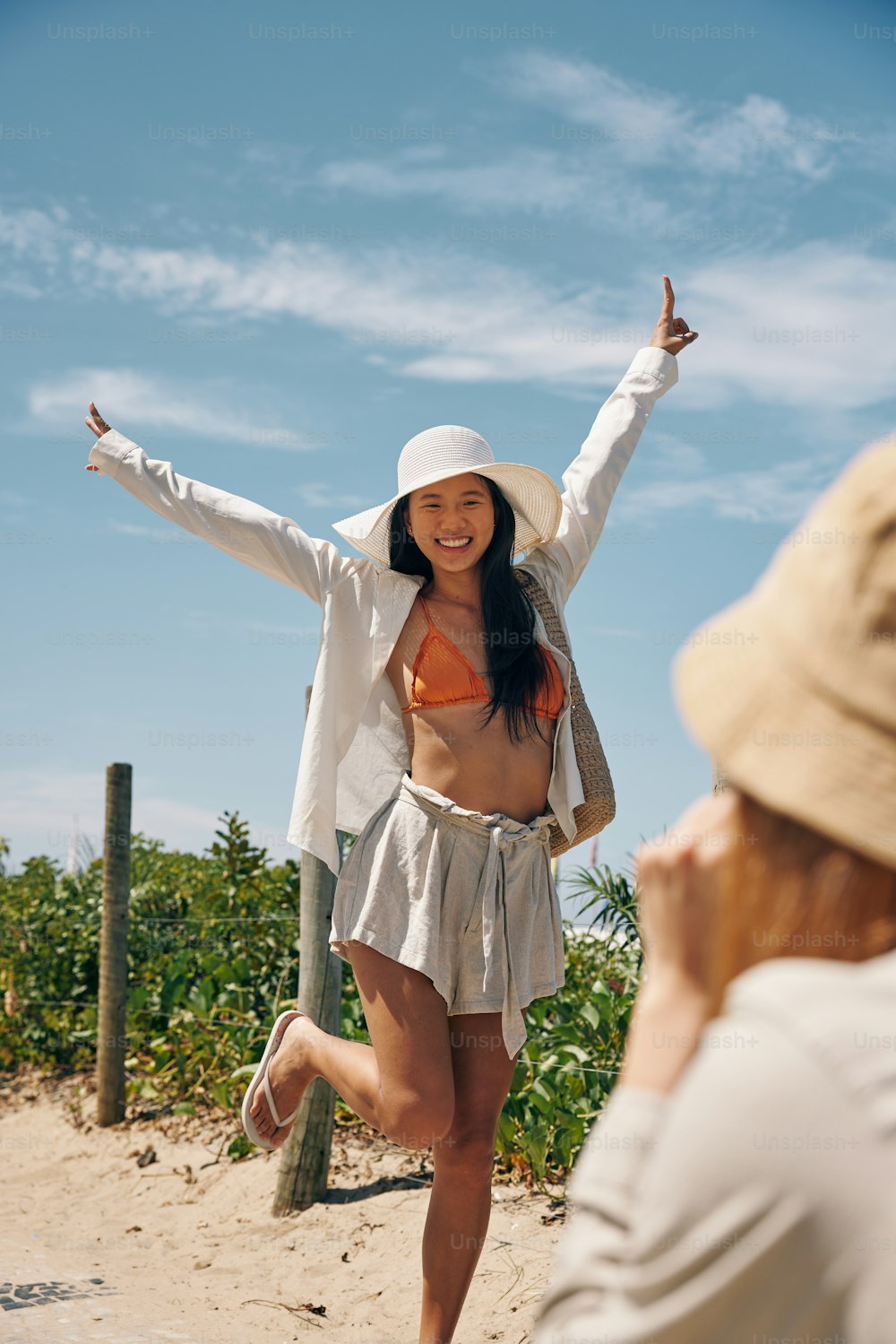 a woman in a bikini top and a hat on a beach