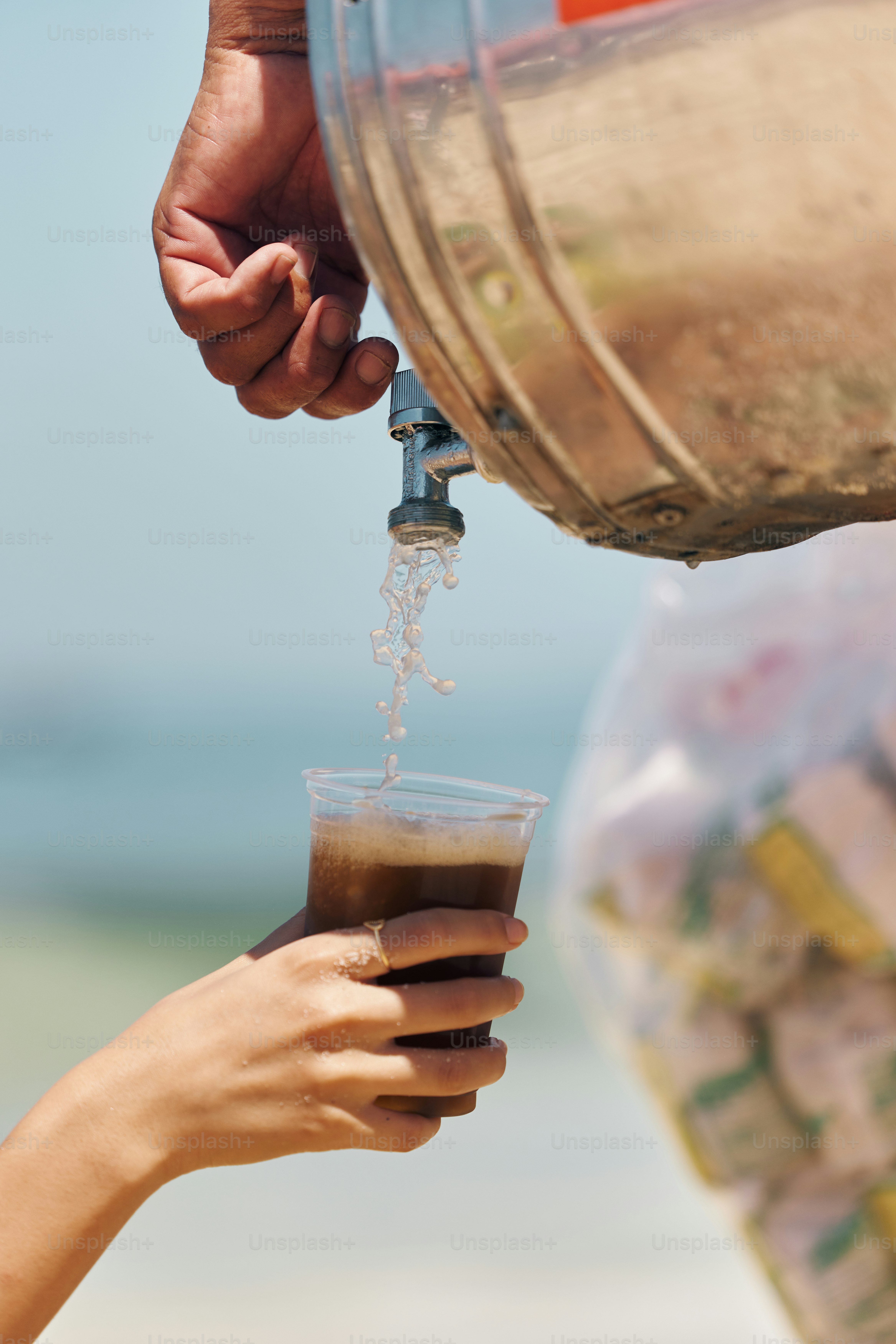 a person pouring a drink into a cup