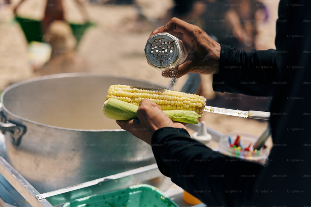 a person pouring corn on the cob into a pot