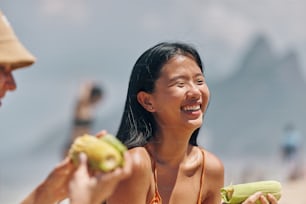 a woman smiling while holding a piece of corn